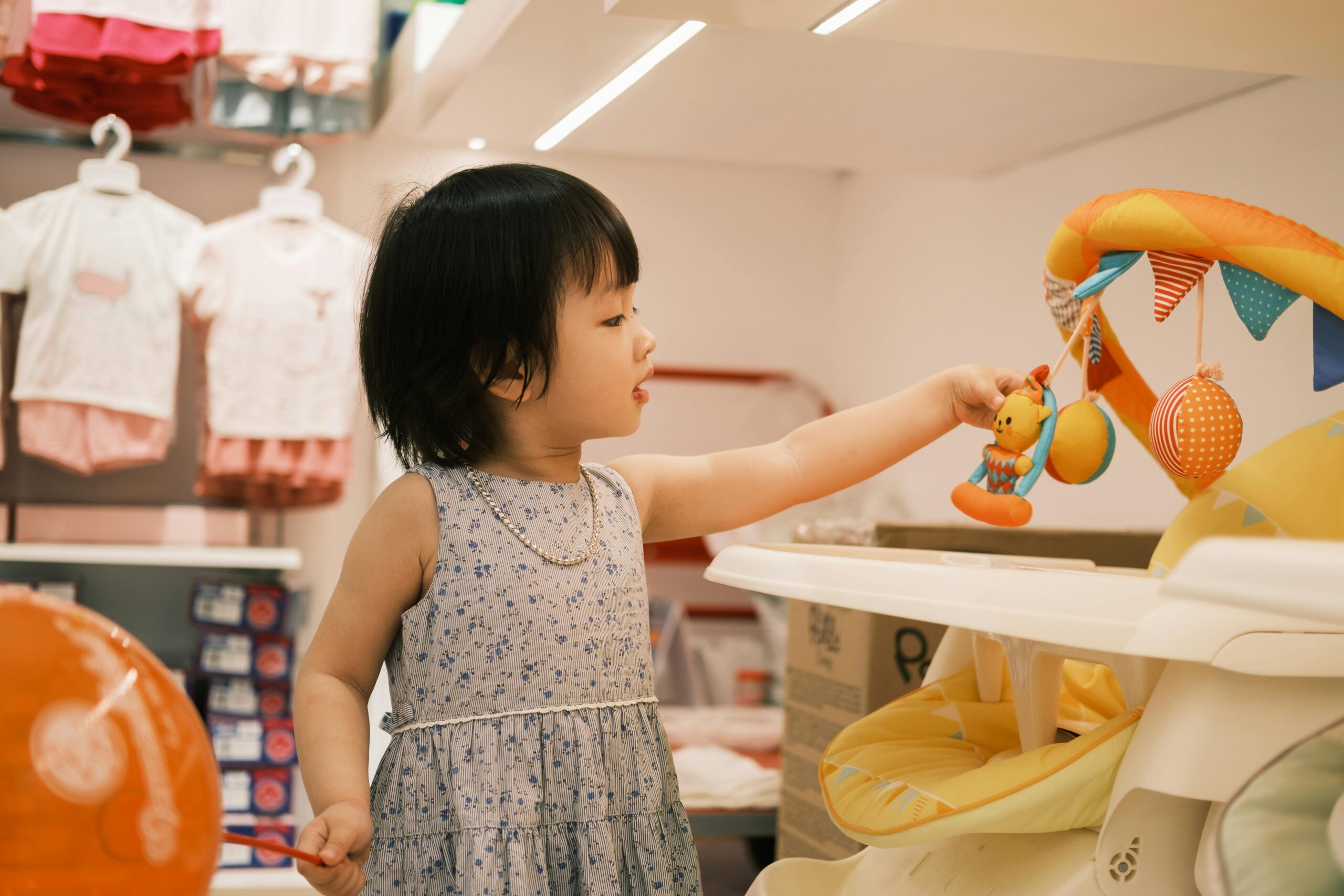 A young child enjoys playing with toys in a vibrant children's store, exploring brightly colored displays.